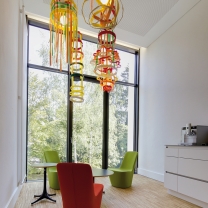Die Teeküche mit raumhoher Fensterfront lädt zur Pause ein. Die farbigen Monopod-Sessel und vom Kunden selbst entworfenen bunten Hängeleuchten bringen Farbe in den Raum.